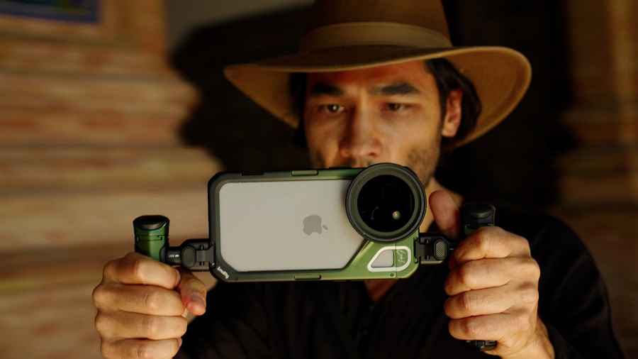 A man in a cowboy hat holding up a camera.