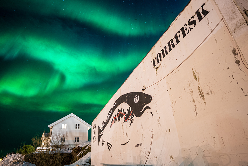 An aurora bore over a building with a graffiti on it.