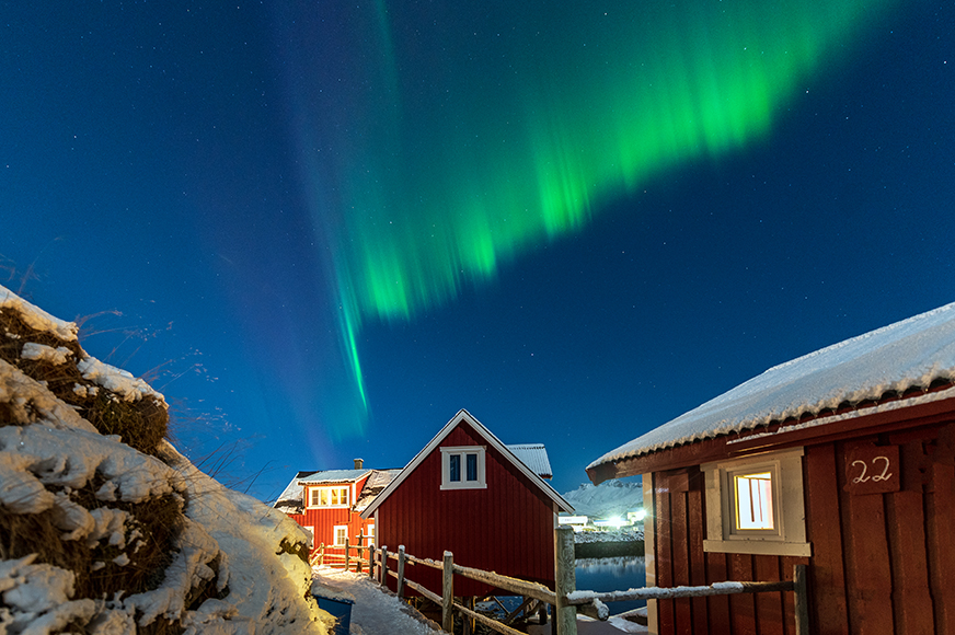 An aurora borealis over a red house.