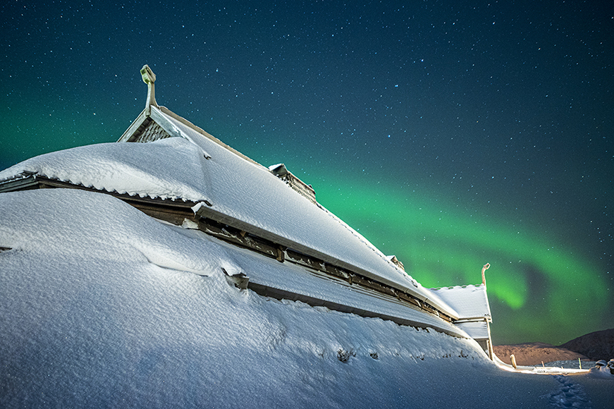 An aurora bore over a snow covered building.