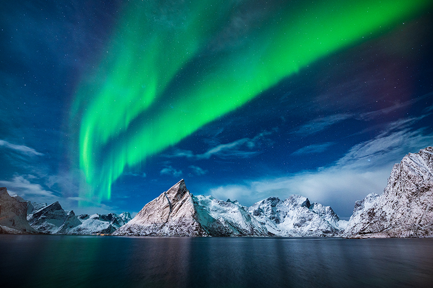 The aurora borealis lights up the sky over a body of water.