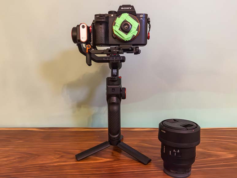 A camera on a gimbal next to a lens.