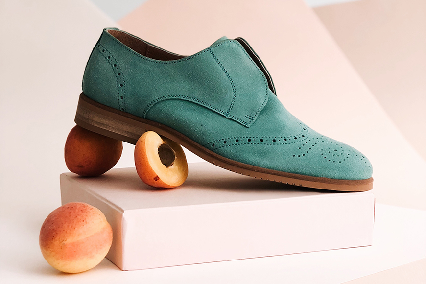 A pair of shoes with peaches on top of a box.
