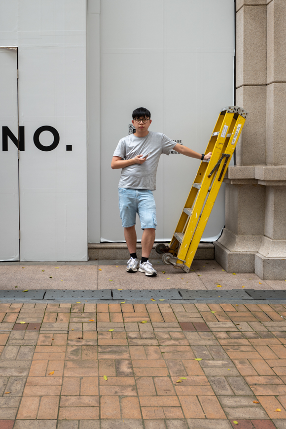 A man standing next to a yellow ladder.