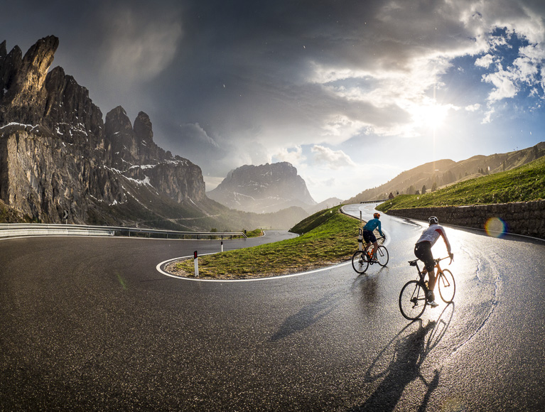 Two cyclists riding down a mountain road.