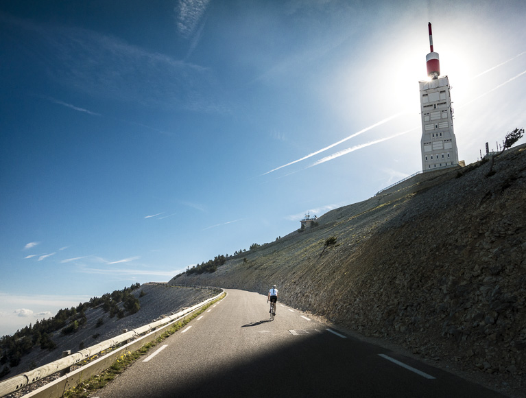 A person is riding a bike down a hill with a tower in the background.