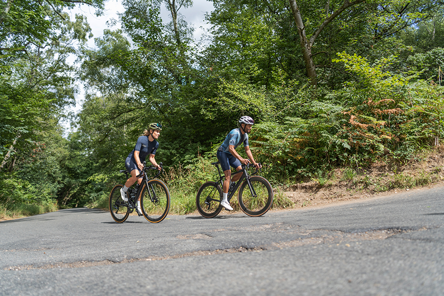 Two people riding bicycles down a paved road.