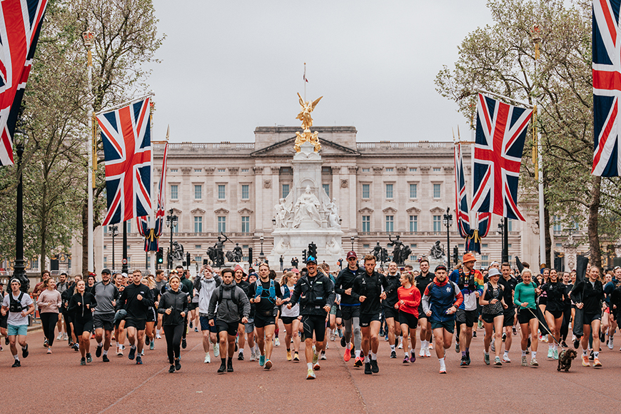 A group of people running in front of buckingham palace.