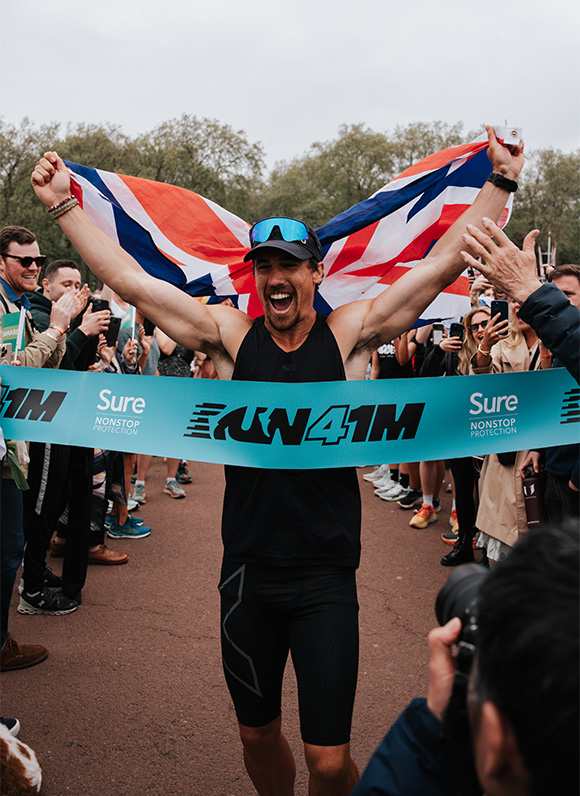 A man celebrates after crossing the finish line of a race.