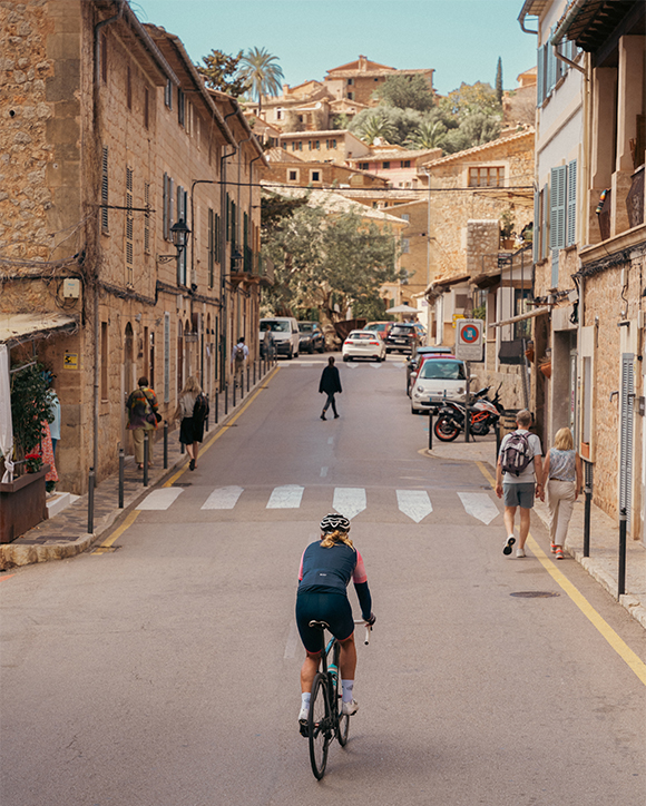 A person riding a bike down a narrow street.