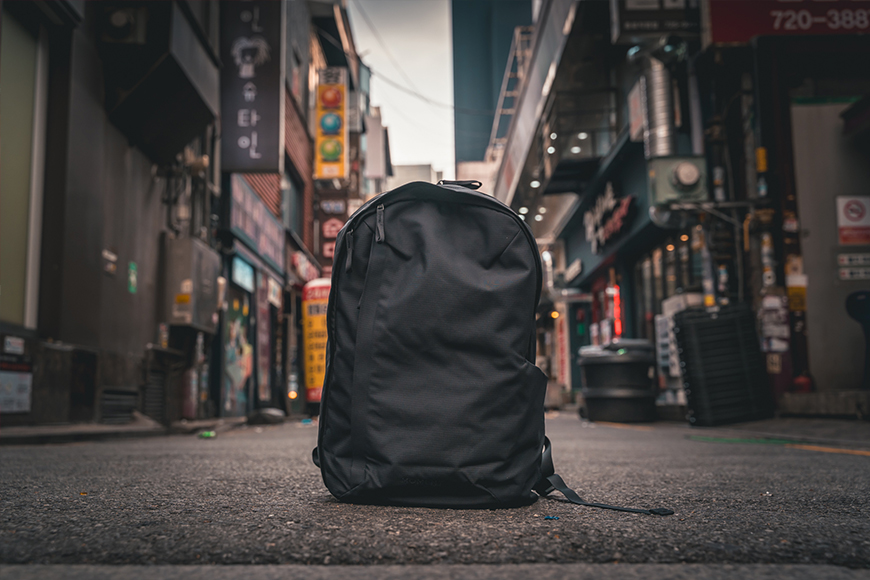 The 21L Moment Everything backpack sitting on a street in a city.