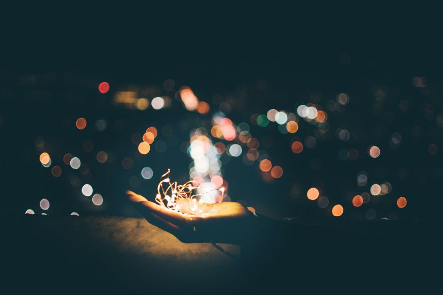 A person holding a sparkler in front of a city.