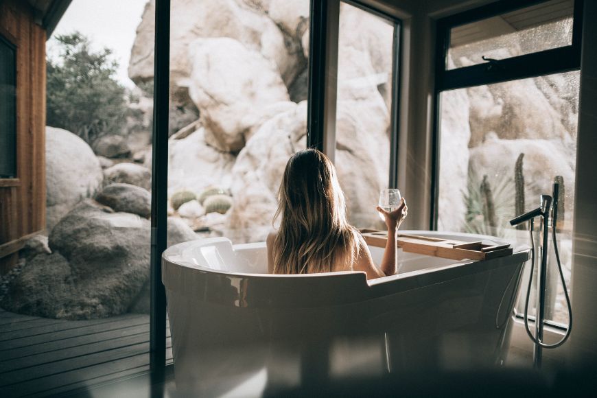 A woman sitting in a bathtub with a glass of wine.